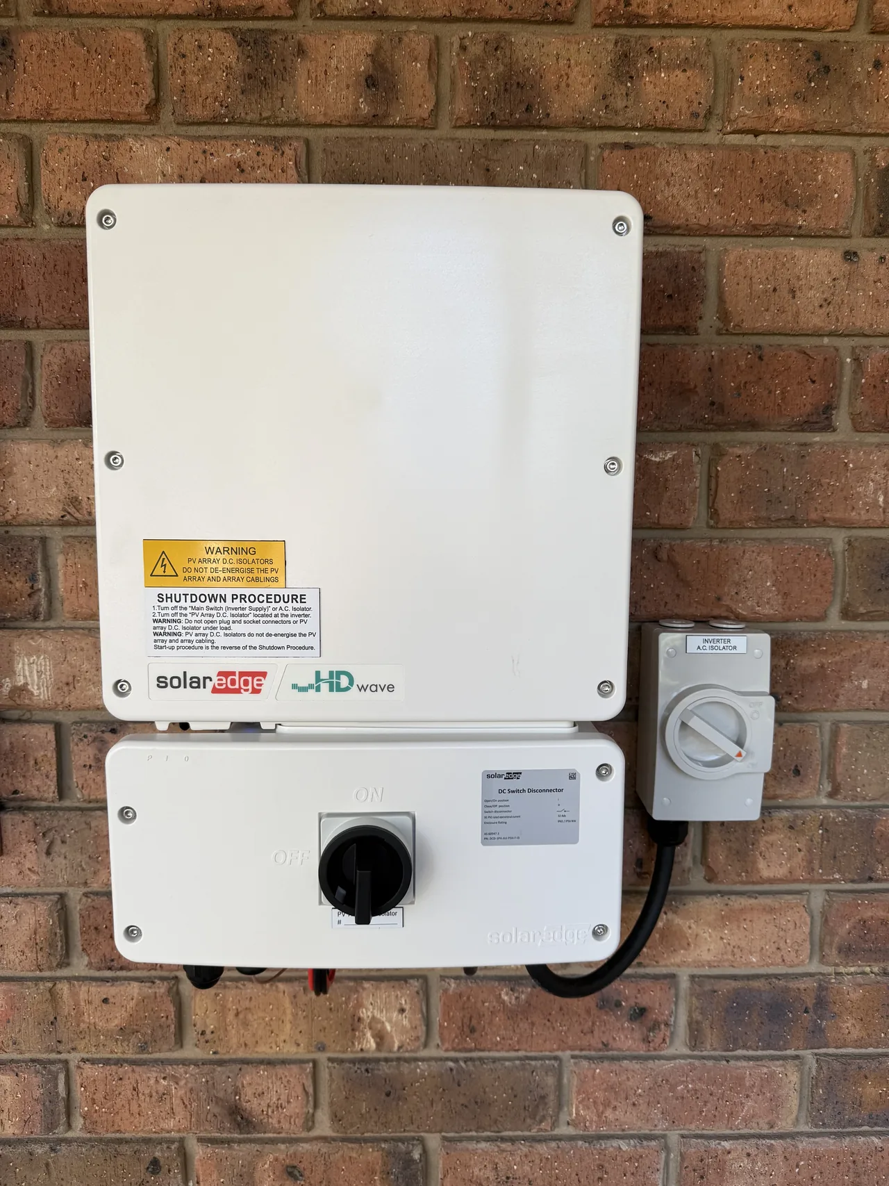 SolarEdge inverter and isolator mounted on the brick wall