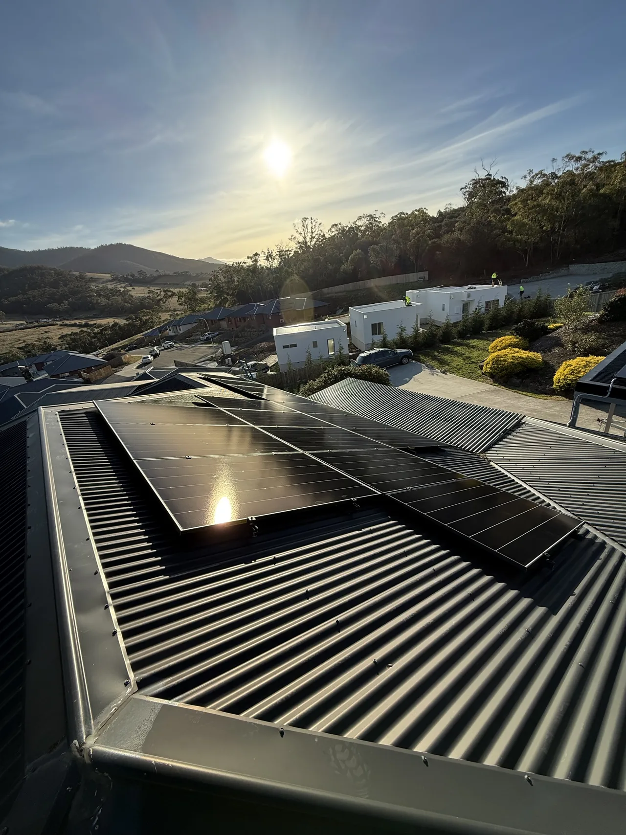 Solar panels on a Claremont roof with the sun low over the hills