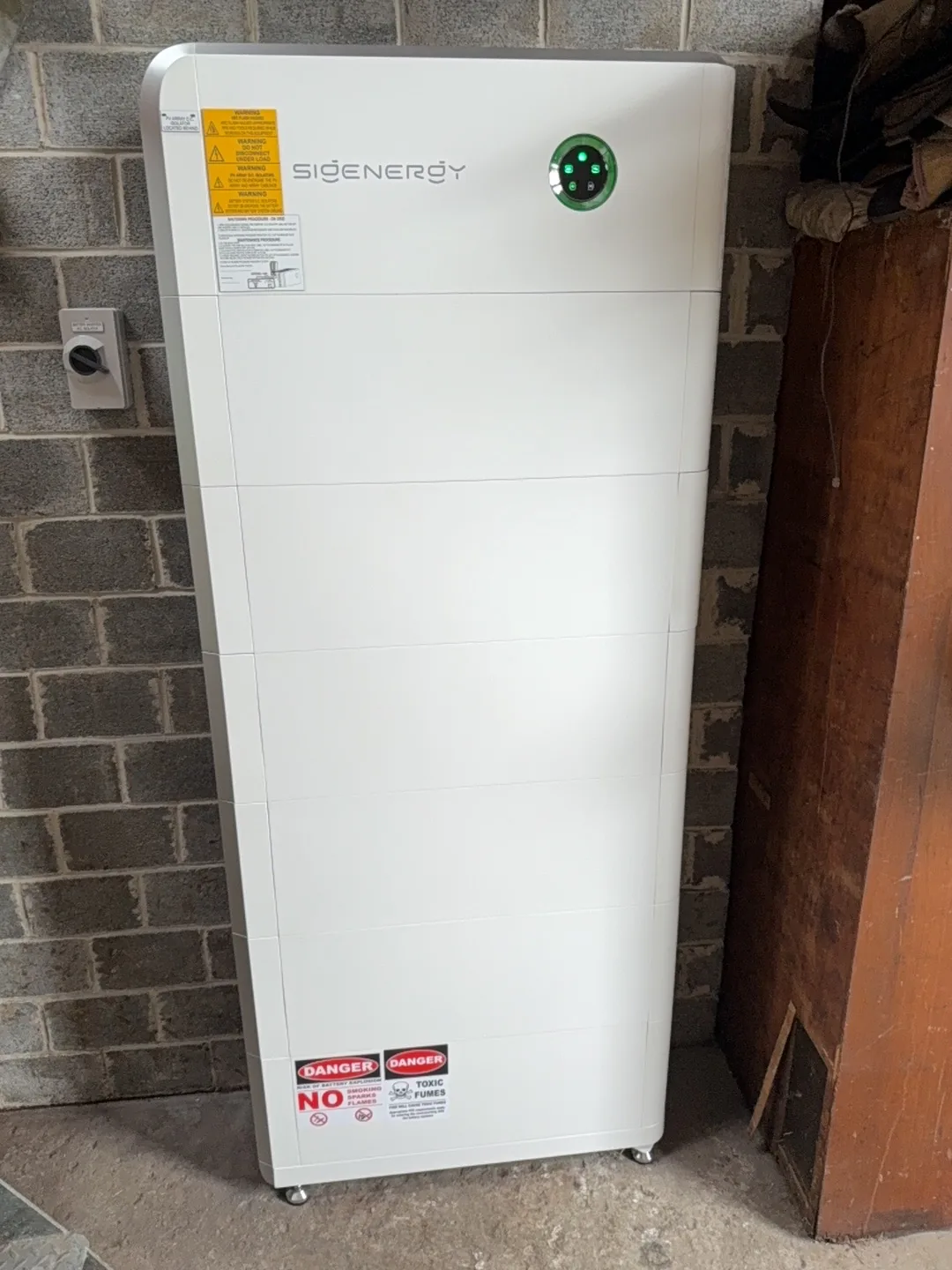Sigenergy battery stack standing against a brick wall