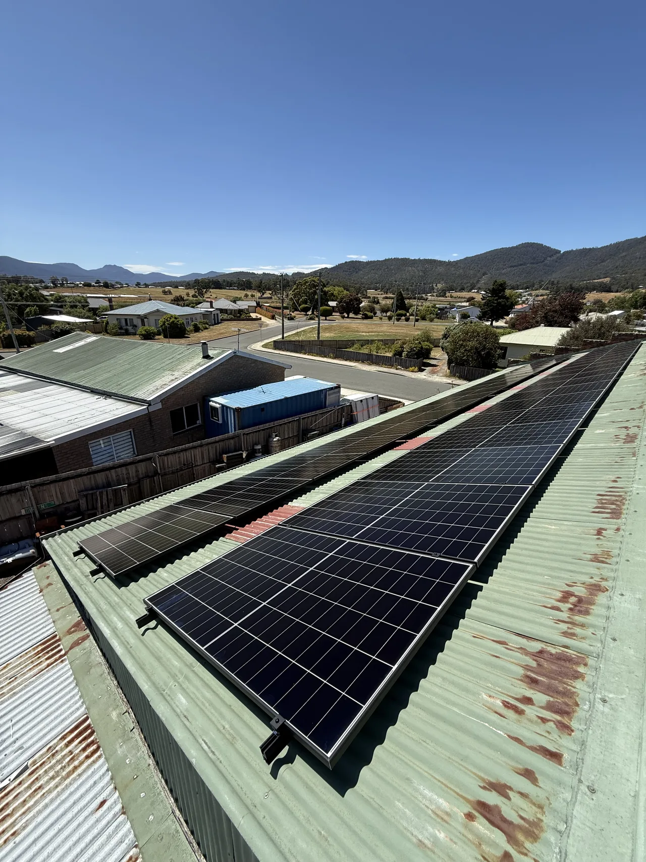 Long runs of solar panels on a Huonville roof with the hills beyond