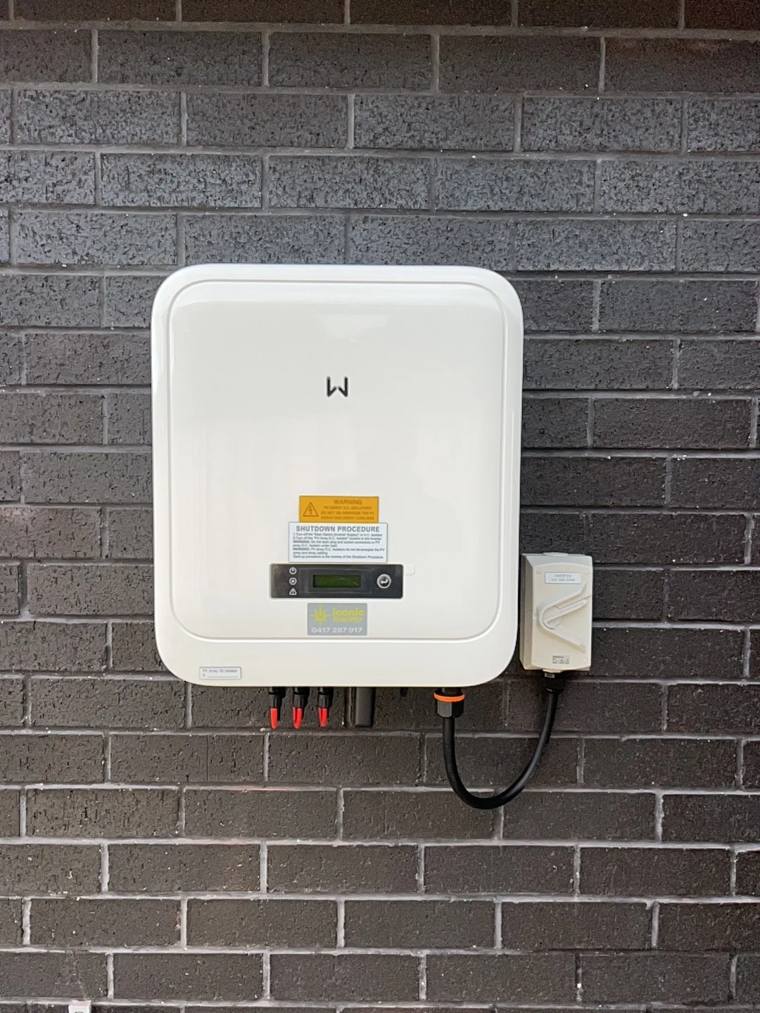 GoodWe inverter mounted on the charcoal brick wall of the house