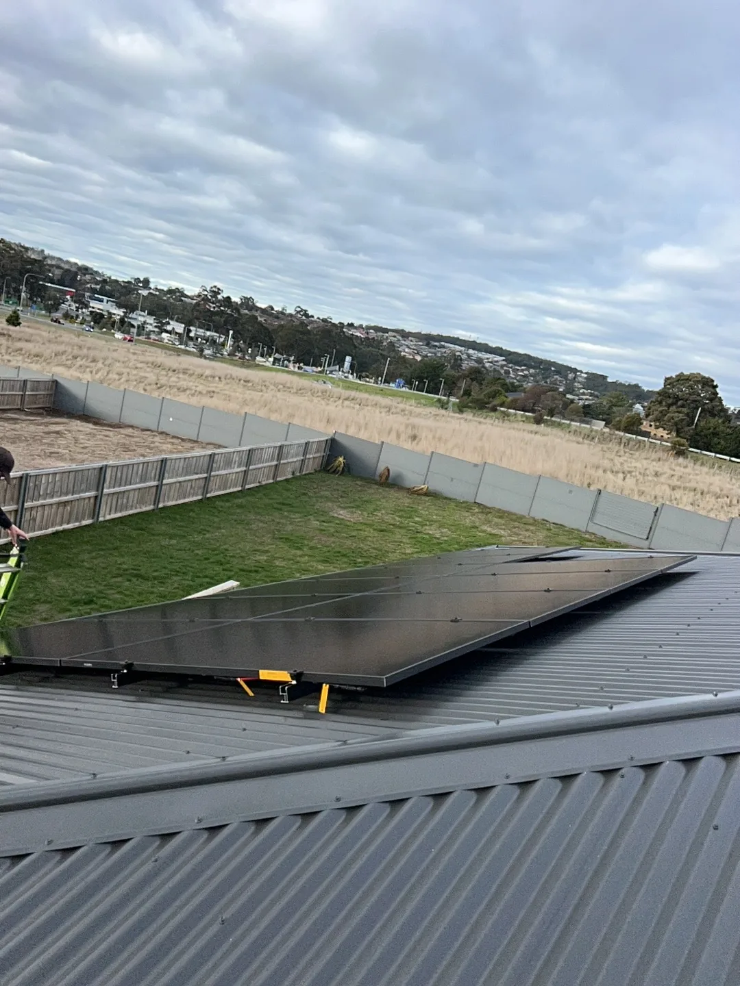 Black solar panels on a Kingston roof with open country and the hills beyond