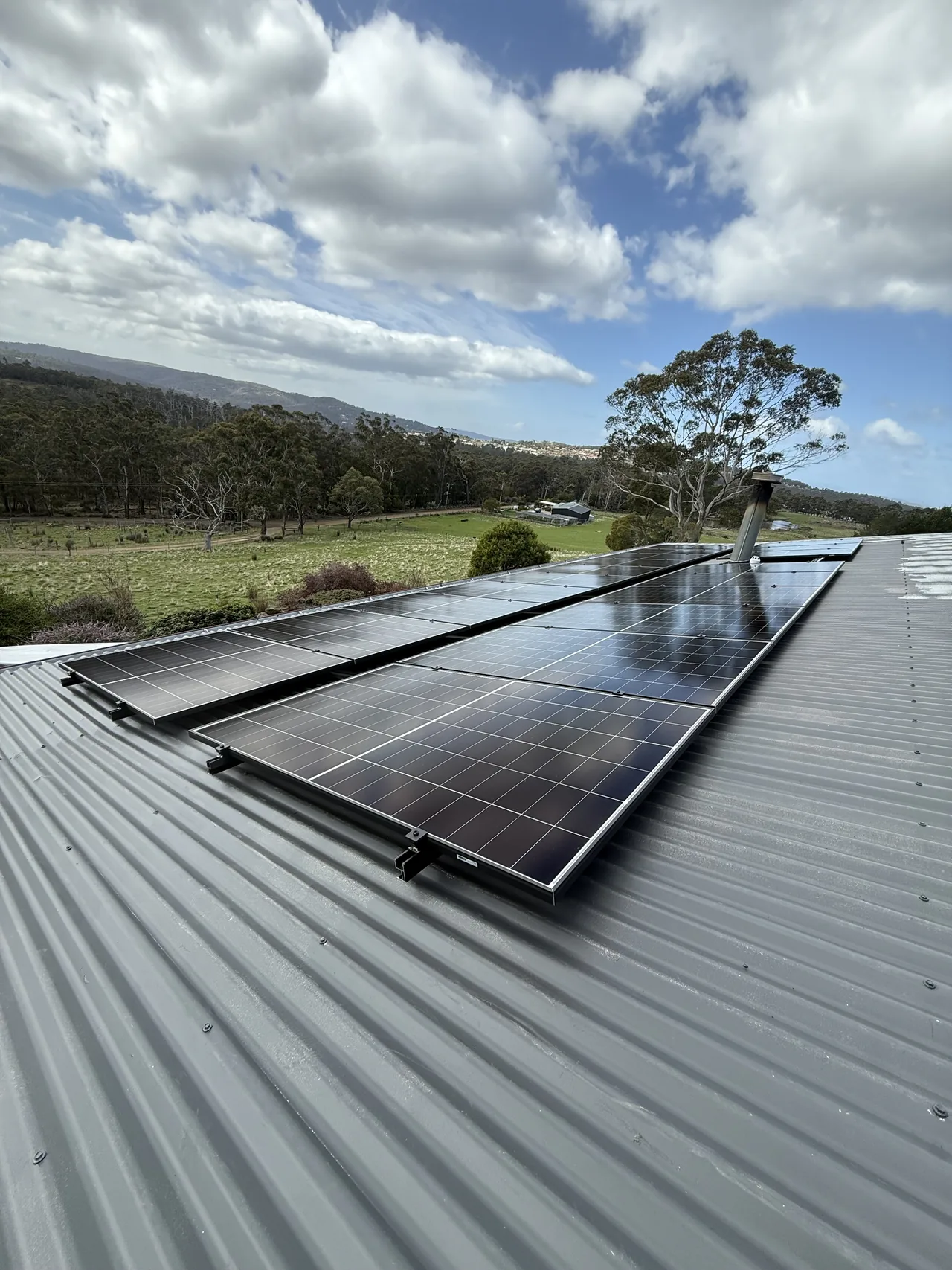 Solar panels across a Kingston roof with farmland and hills behind