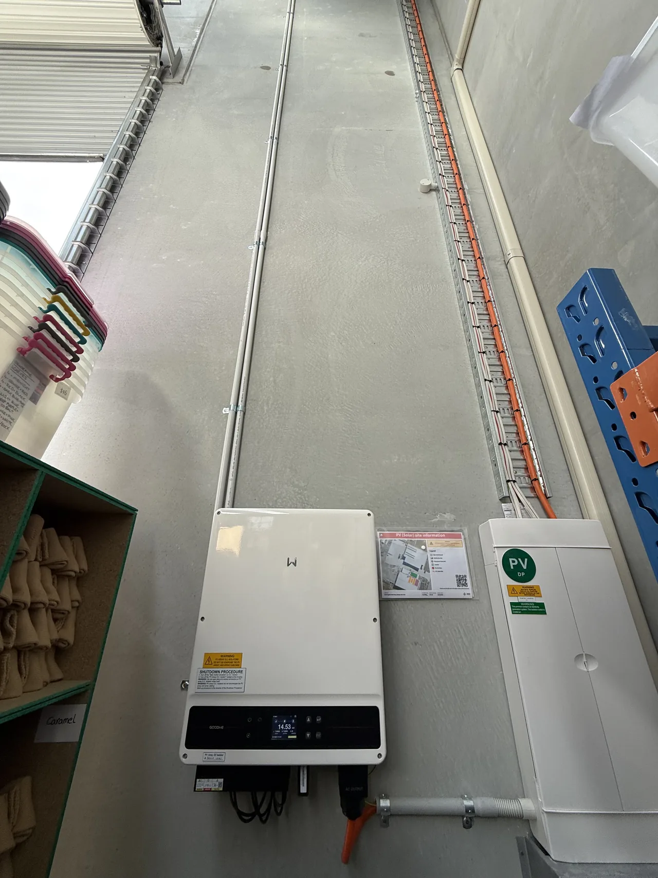 The inverter installed on the warehouse wall beside the racking