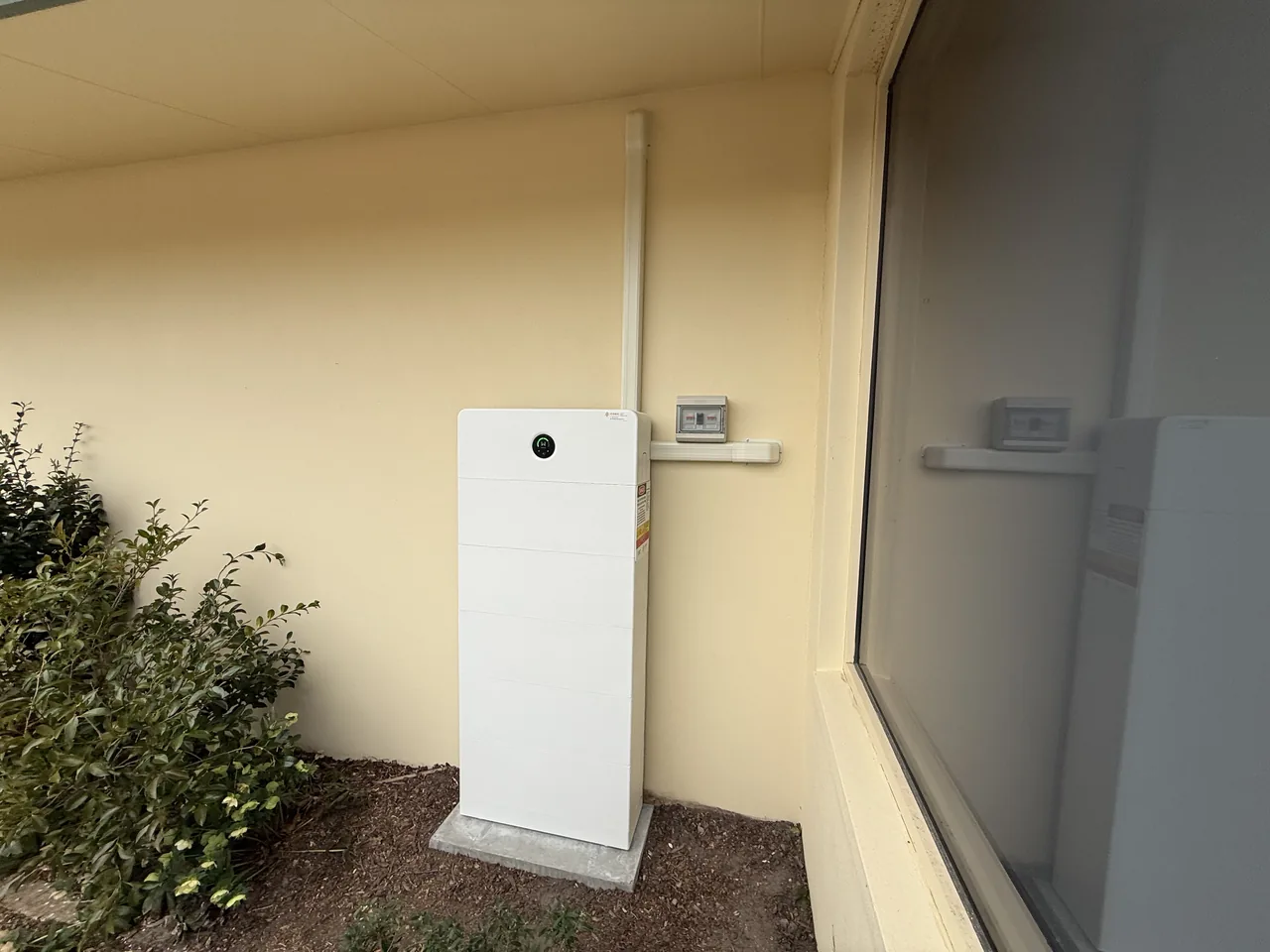 GoodWe battery modules in a ground-mounted enclosure against the wall of the house