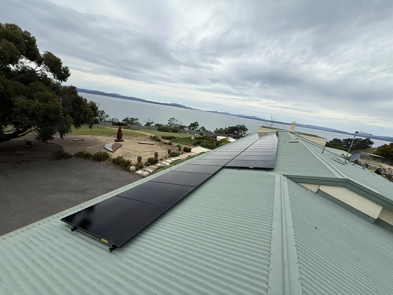 Solar array running along the ridge of the Sandford roof, with the garden and coastline beyond